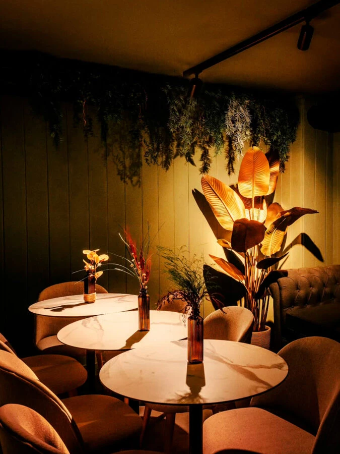 Interior del salón comedor del restaurante HDDN Madrid con luz tenue y decoración vegetal.