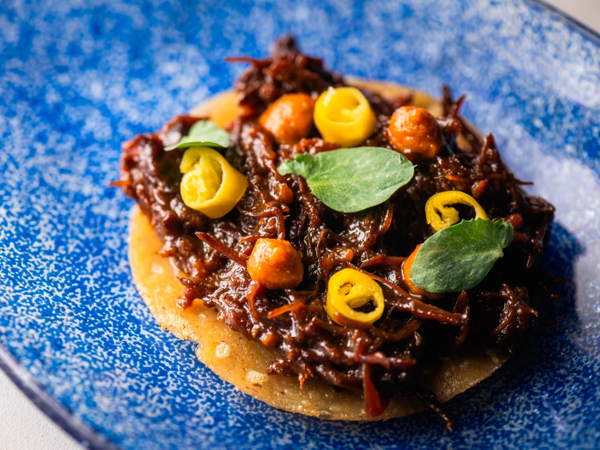 Taco de porco celta del restaurante HDDN Madrid con guiso y chiles.