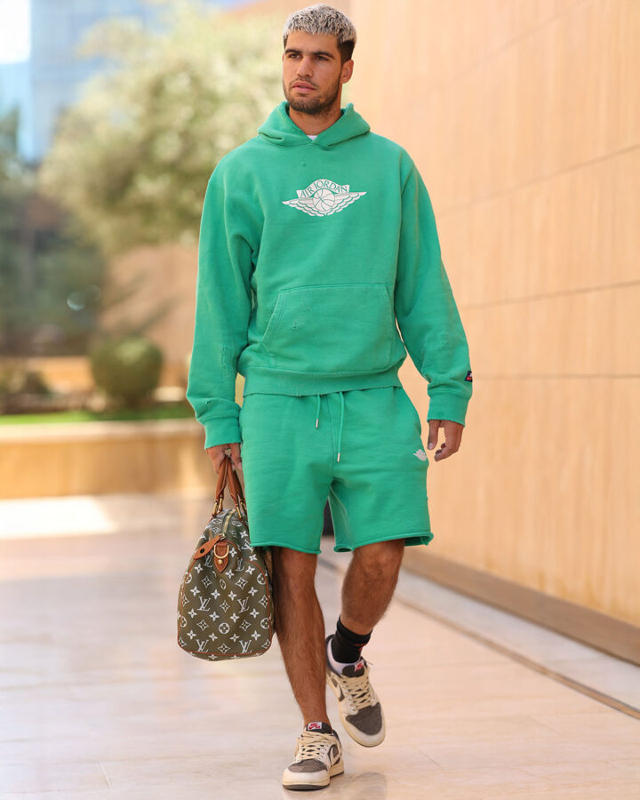 Carlos Alcaraz paseando por Riad con un conjunto verde y bolso Keepall Bandoulière 45 de Louis Vuitton.