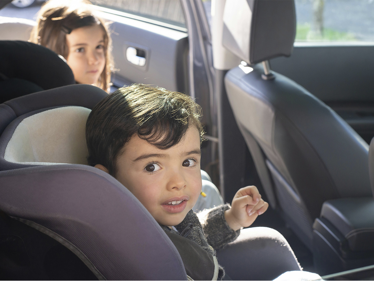 dos niños pequeños sentados en los asientos traseros de un coche en sus sillitas