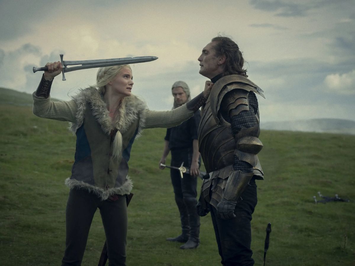 Escena de la cuarta temporada de la serie The Witcher en la que se ve a Liam Hemsworth siendo agarrado por el cuello y apuntado con una espada por una mujer rubia