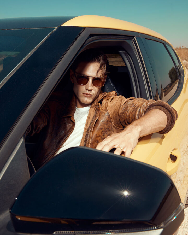 Modelo al volante del nuevo Ford Capri 2025 con chaqueta de cuero marrón.