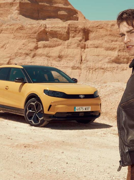 Modelo con chaqueta de aviador frente al nuevo Ford Capri 2025 en color amarillo.