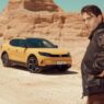 Modelo con chaqueta de aviador frente al nuevo Ford Capri 2025 en color amarillo.
