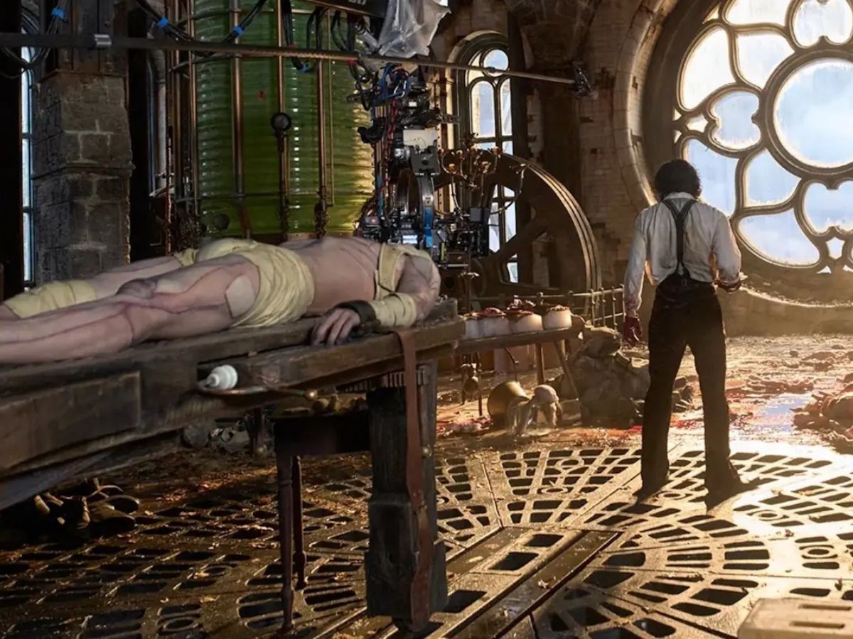 Escena de la película Frankestein que muestra a Oscar Isaac de espaldas y un cadaver en una mesa