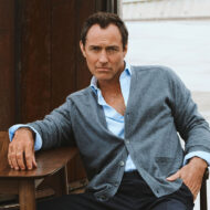 Jude Law con cárdigan gris y camisa abierta en la campaña de Emidio Tucci otoño-invierno 2025