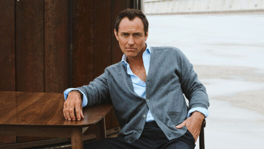 Jude Law con cárdigan gris y camisa abierta en la campaña de Emidio Tucci otoño-invierno 2025