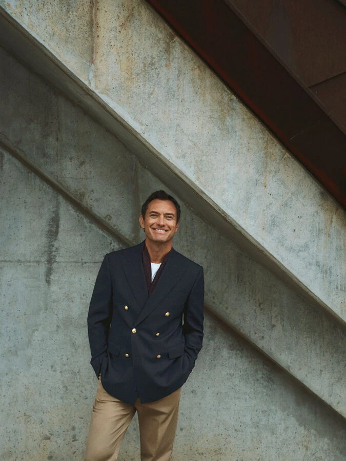 Jude Law con americana azul marino cruzada y pantalón beige en la campaña de Emidio Tucci
