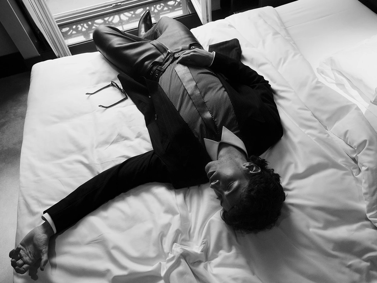 Manu Ríos tumbado en la cama de la suite de su hotel vestido de Tom Ford antes de acudir al desfile del diseñador