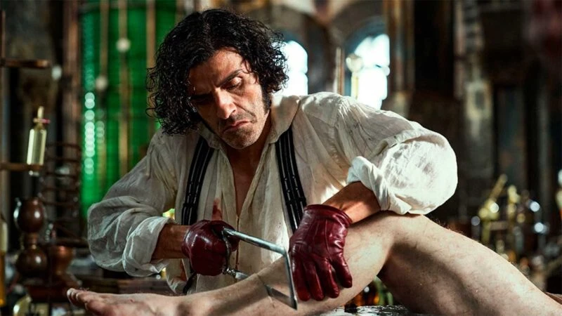 El actor Oscar Isaac en una escena de la película Frankestein, en la que se le ve amputando una pierda a un cadáver