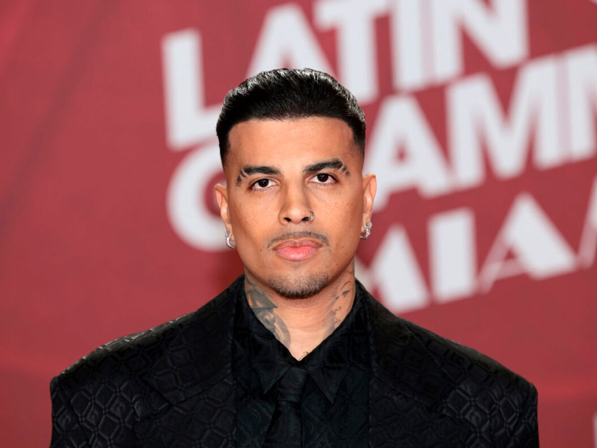 Retrato del cantante Rauw Alejandro en la red carpet de los Latin Grammy, vestido con un traje de chaqueta negro