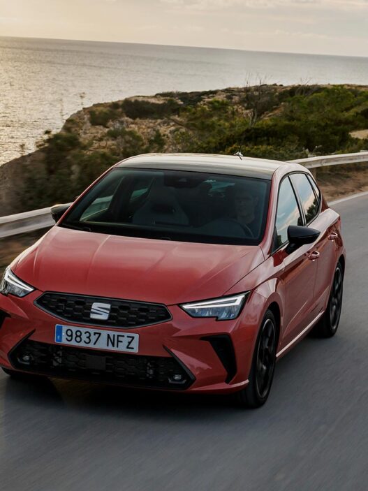 SEAT Ibiza 2025 en color rojo circulando por carretera junto al mar