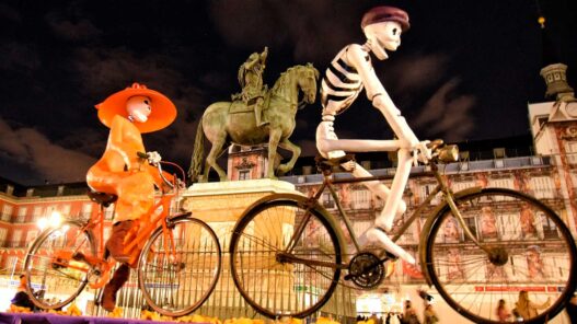 Fotografía de la Plaza Mayor de Madrid adornada de Halloween con figuras enormes de esqueletos montando en bicicleta.