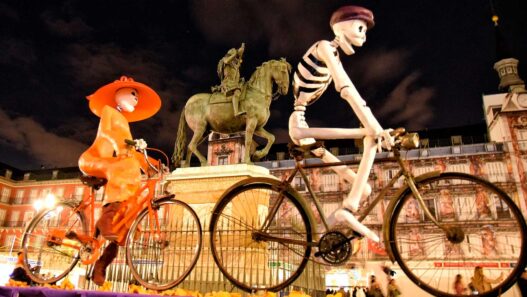 Fotografía de la Plaza Mayor de Madrid adornada de Halloween con figuras enormes de esqueletos montando en bicicleta.