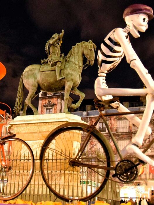 Fotografía de la Plaza Mayor de Madrid adornada de Halloween con figuras enormes de esqueletos montando en bicicleta.