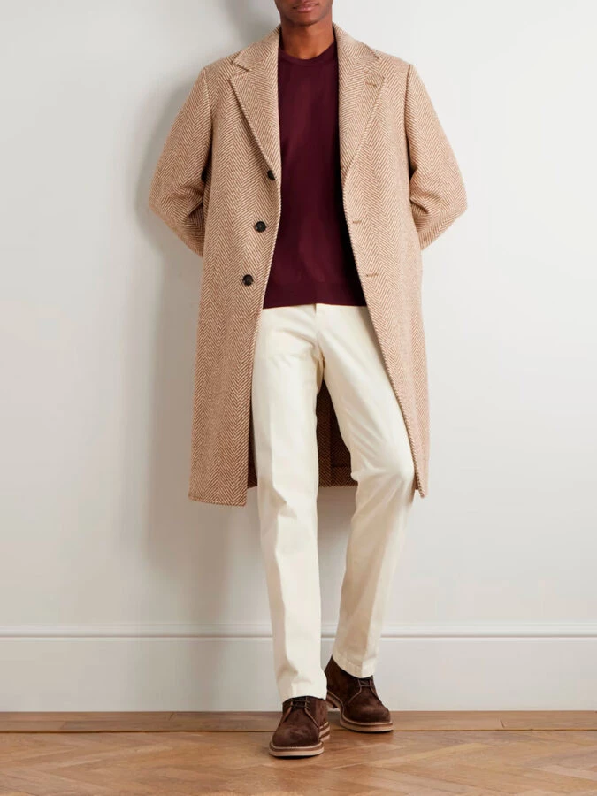 Look de hombre con jersey burdeos, abrigo de espiga marrón, pantalón blanco y botines de ante