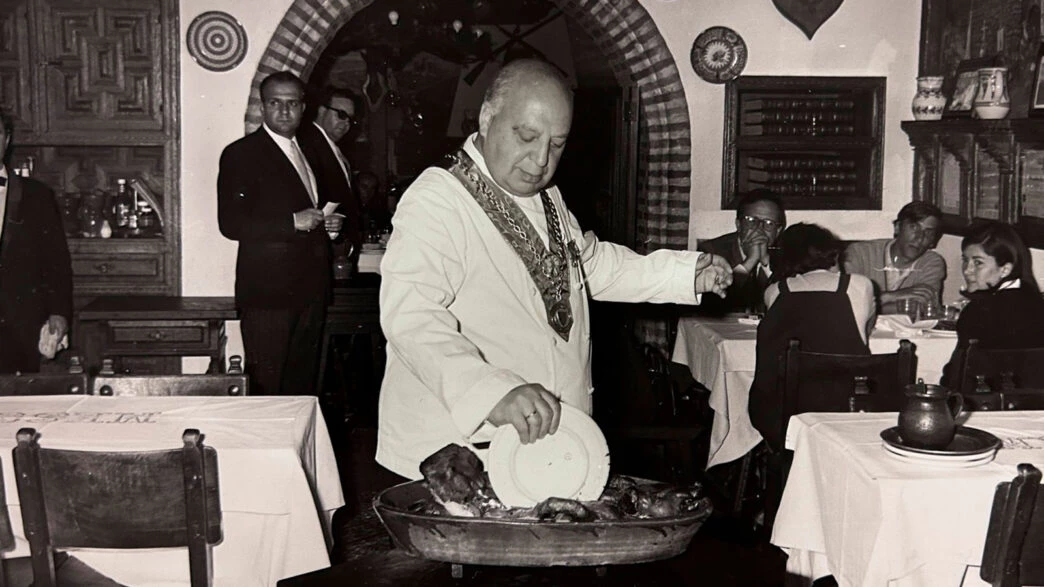 Cándido partiendo el cochinillo con un plato en el Mesón de Cándido, Segovia.