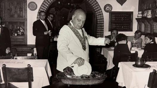Cándido partiendo el cochinillo con un plato en el Mesón de Cándido, Segovia.