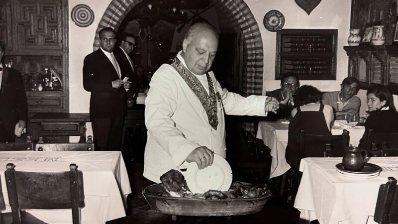 Cándido partiendo el cochinillo con un plato en el Mesón de Cándido, Segovia.