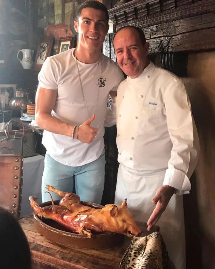 Cristiano Ronaldo junto al chef del Mesón de Cándido con un cochinillo asado en la mesa.
