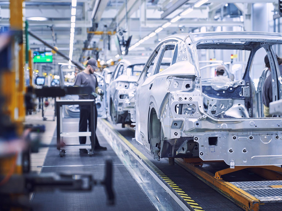 Fabrica de coches en la que se ve la estructura de unos coches siendo revisada por un técnico