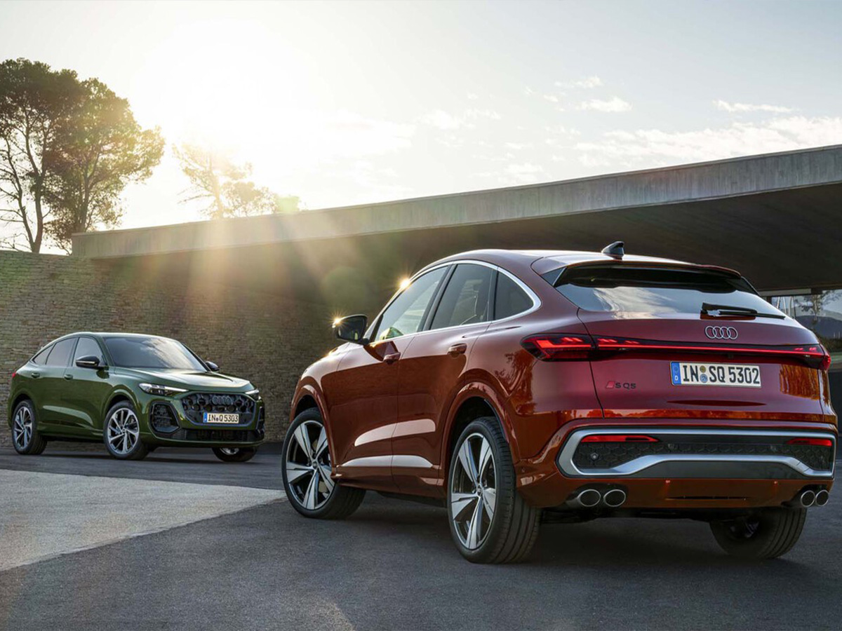 Dos coches Audi Q5 e-hybrid uno frente a otro, uno de color rojo y otro de color verde.