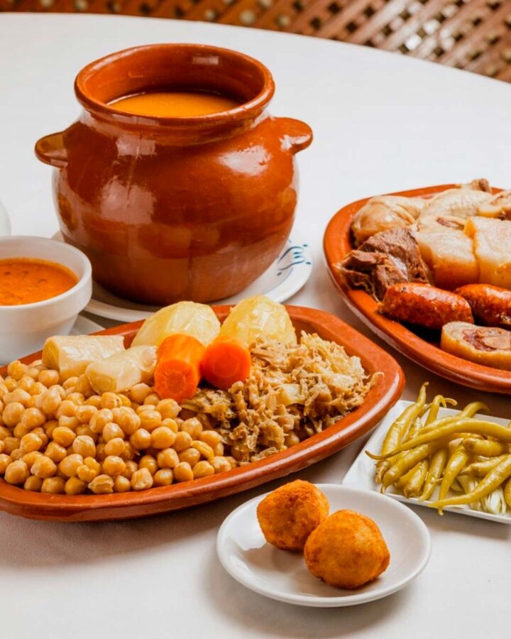 Cocido madrileño de tres vuelcos servido en Casa Carola, con garbanzos, verduras y carnes tradicionales.