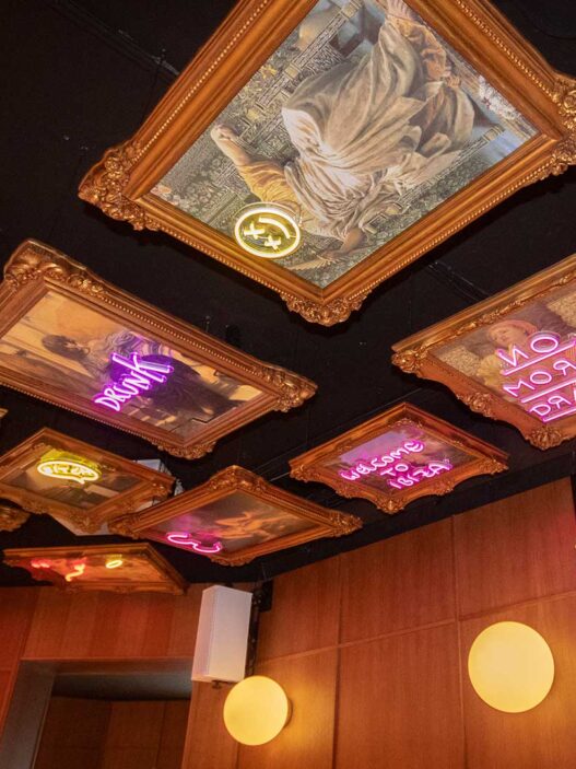 Techo decorado con marcos dorados y neones de colores en el restaurante Memories del Palacio de Liria.