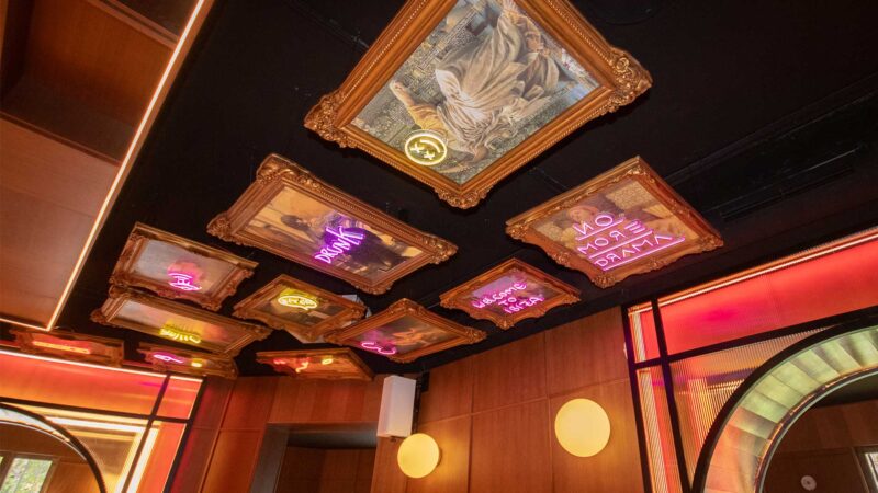 Techo decorado con marcos dorados y neones de colores en el restaurante Memories del Palacio de Liria.