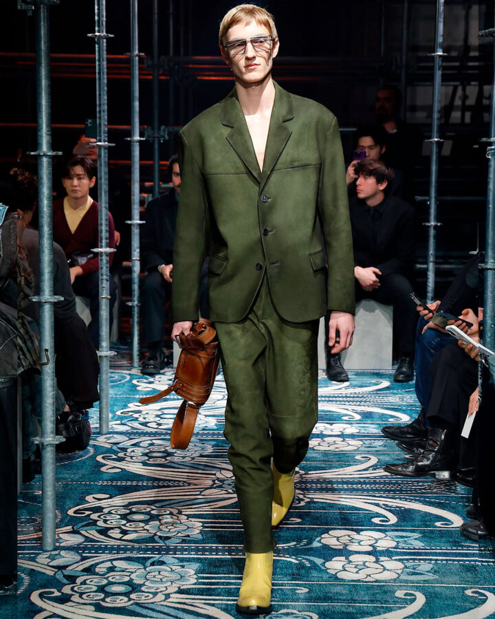 Modelo desfilando durante el desfile de Prada otoño 2025 con un traje verde y botines amarillos