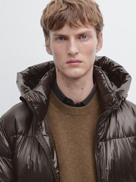 Modelo luciendo abrigo de plumón marrón de Massimo Dutti con capucha y cuello alto.