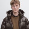 Modelo luciendo abrigo de plumón marrón de Massimo Dutti con capucha y cuello alto.