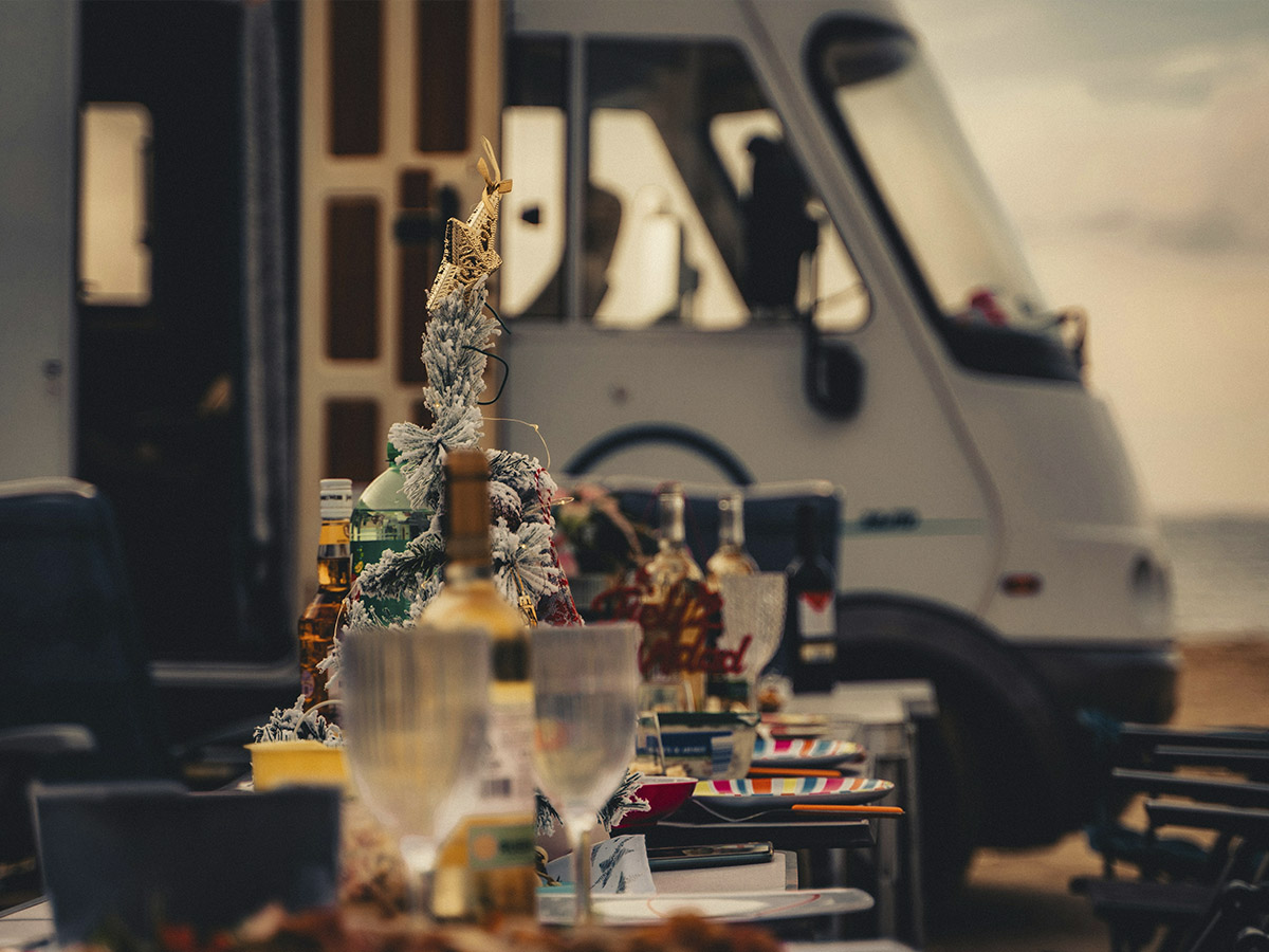mesa navideña con comida en un exterior y de fondo se ve una autocaravana en segundo plano