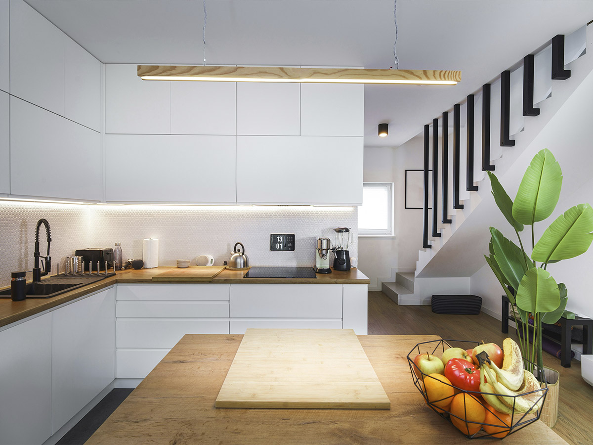 interior de una cocina muy elegante y minimalista con una isla en el centro y unas escaleras al fondo