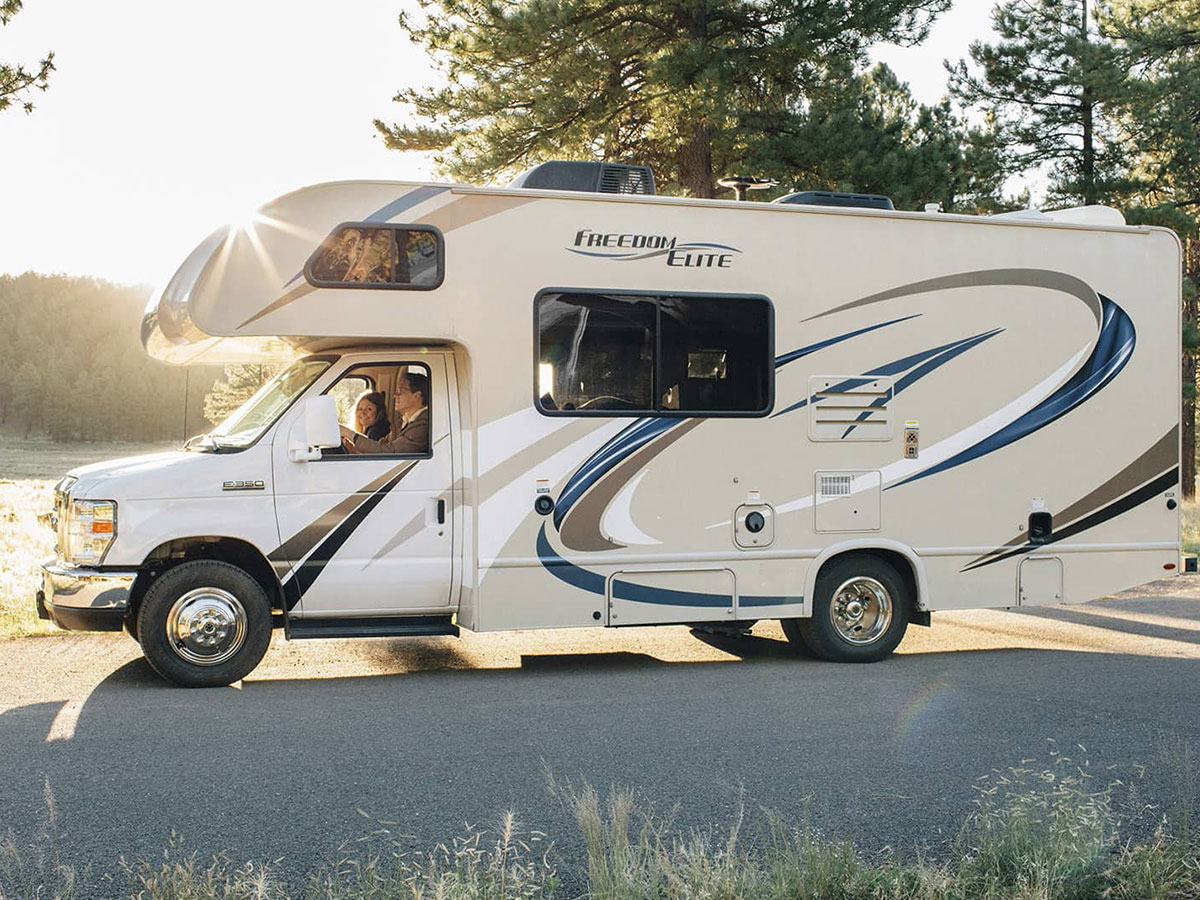 Caravana blanca estacionada en una carretera de un bosque