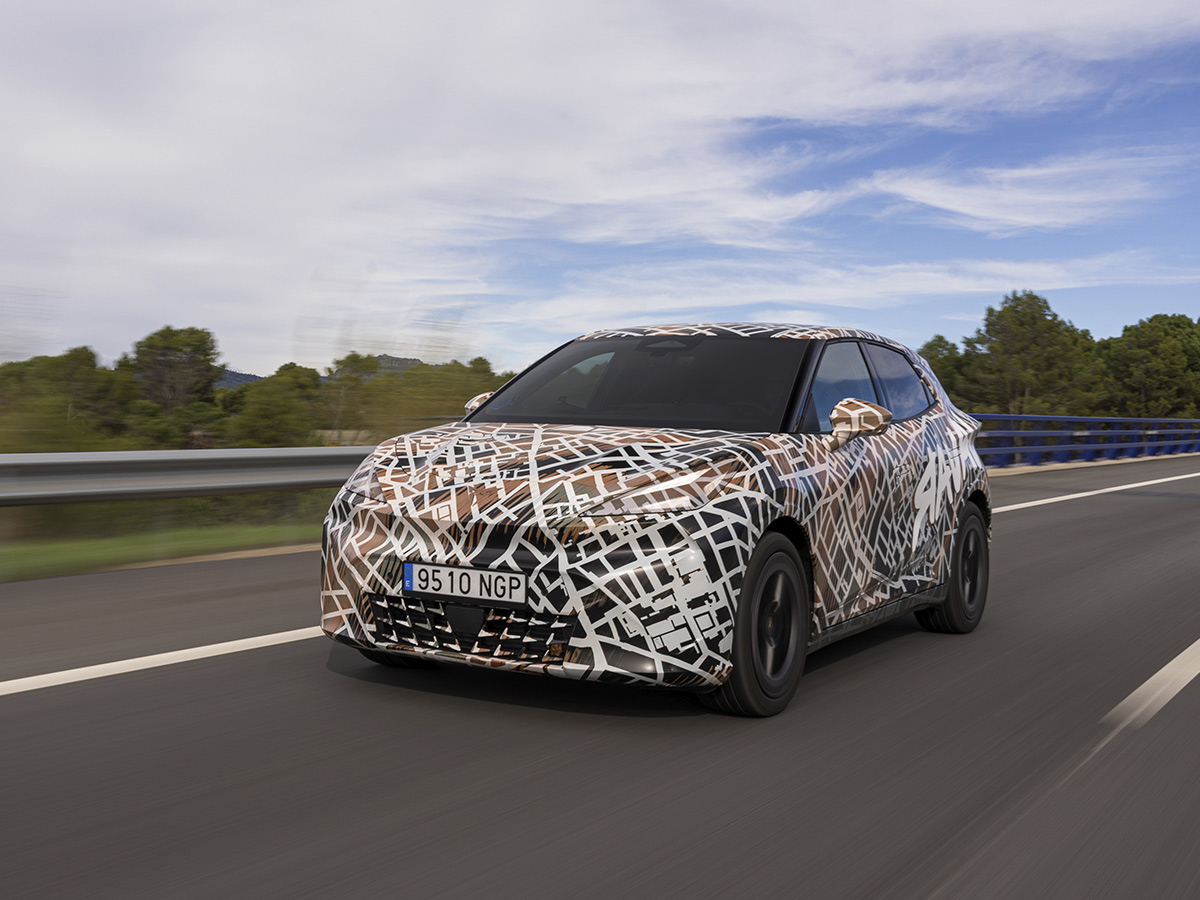 Cupra Raval de pruebas avanzando por carretera con su vinilo de camuflaje característico.