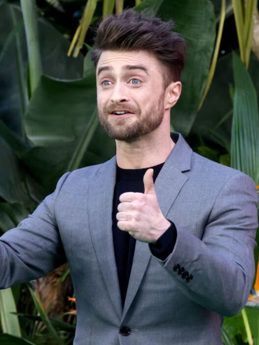 Daniel Radcliffe vestido con un traje gris y levantando los pulgares