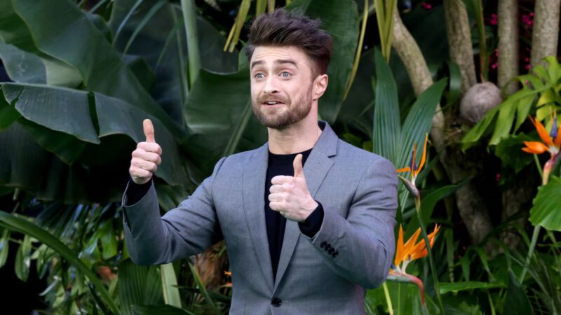 Daniel Radcliffe vestido con un traje gris y levantando los pulgares