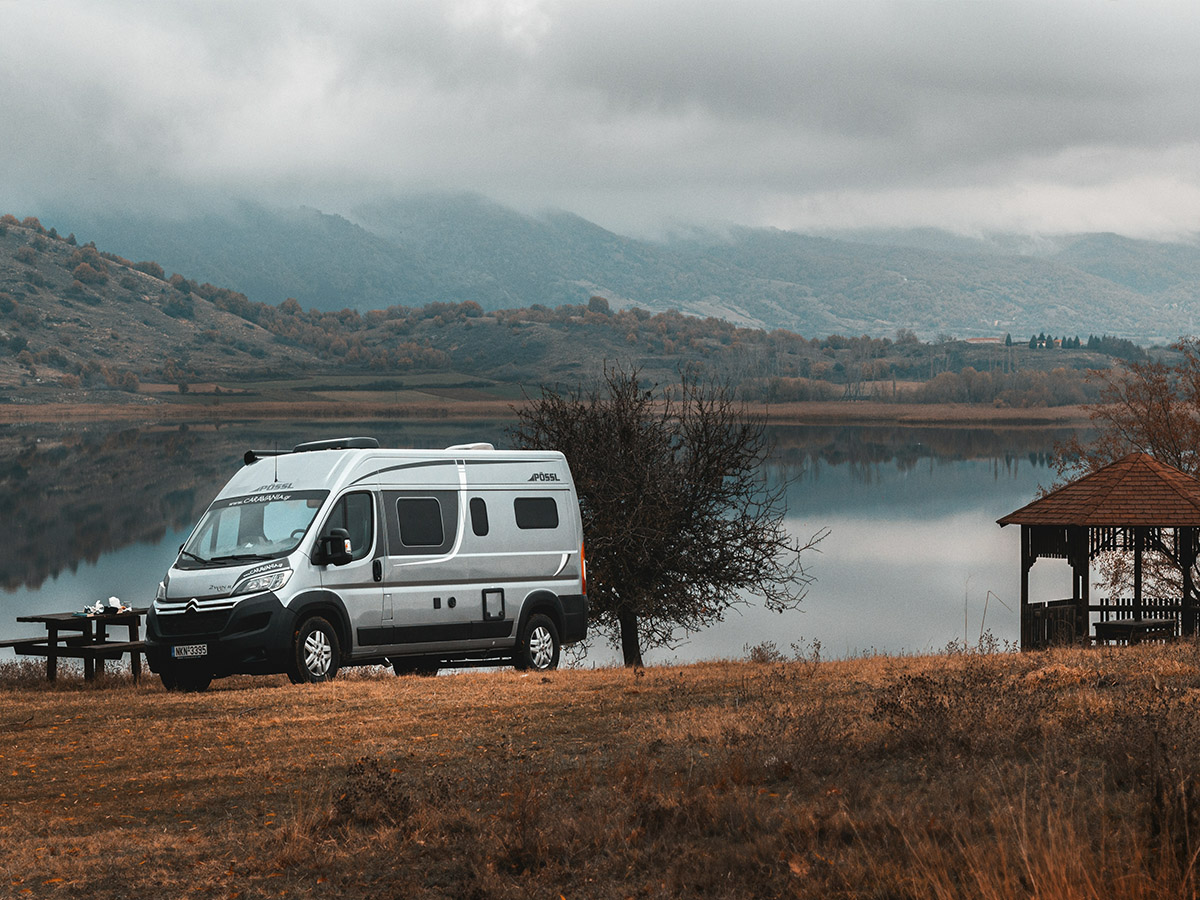 autocaravana moderna aparcada en un campo con un lago en otoño, imagen de estilo nostálgico