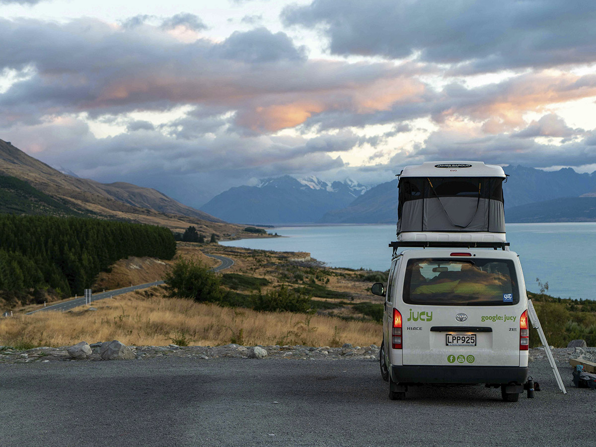 Autocaravana aparcada en un mirado con vistas a una playa amaneciendo