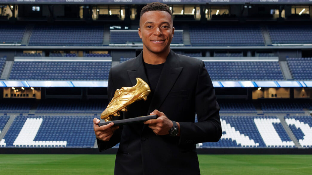 Kylian Mbappé posando con la Bota de Oro 2025 vestido con un traje negro de Dior.