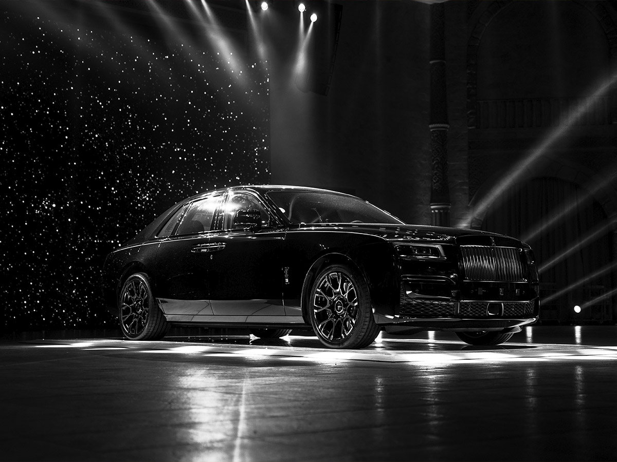 Bentley negro bajo luces escénicas, reflejo del lujo contemporáneo y la excelencia británica en diseño y confort.