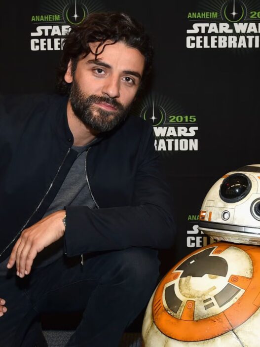 Fotografía del actor Oscar Isaac apoyado sobre una maqueta del robot R2D2 en una presentación de Star Wars.