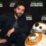 Fotografía del actor Oscar Isaac apoyado sobre una maqueta del robot R2D2 en una presentación de Star Wars.