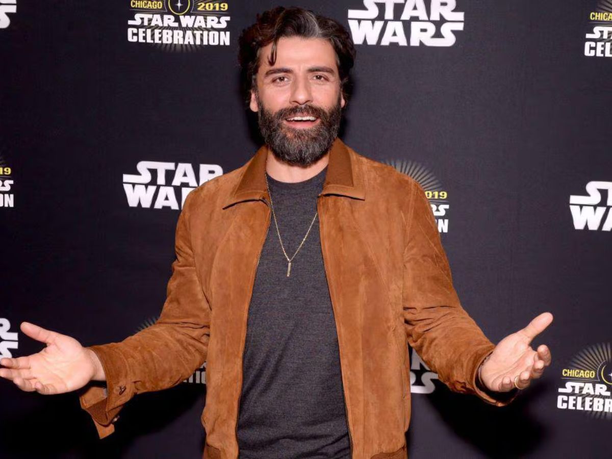 Oscar Isaac posa alegre, con barba y con las manos abiertas en un photocall de Star Wars