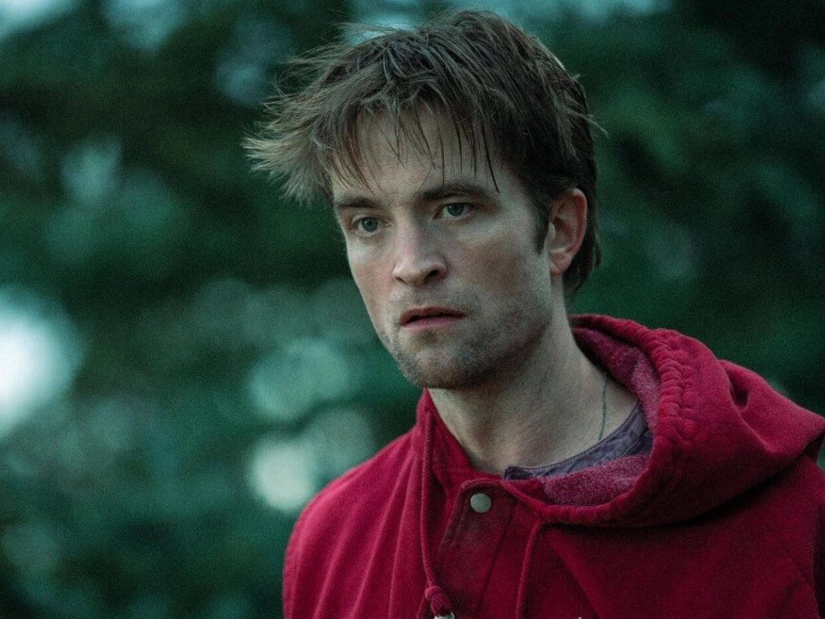 Escena de Robert Pattinson en Die My Love, con una sudadera roja y cara triste
