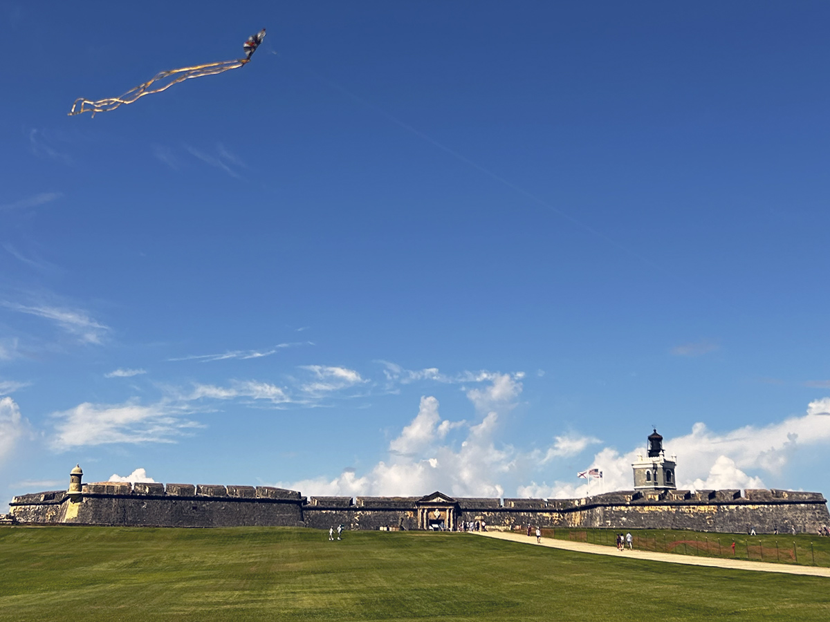 Explanada del Fuerte San Felipe del Morro con una cometa volando sobre el césped.