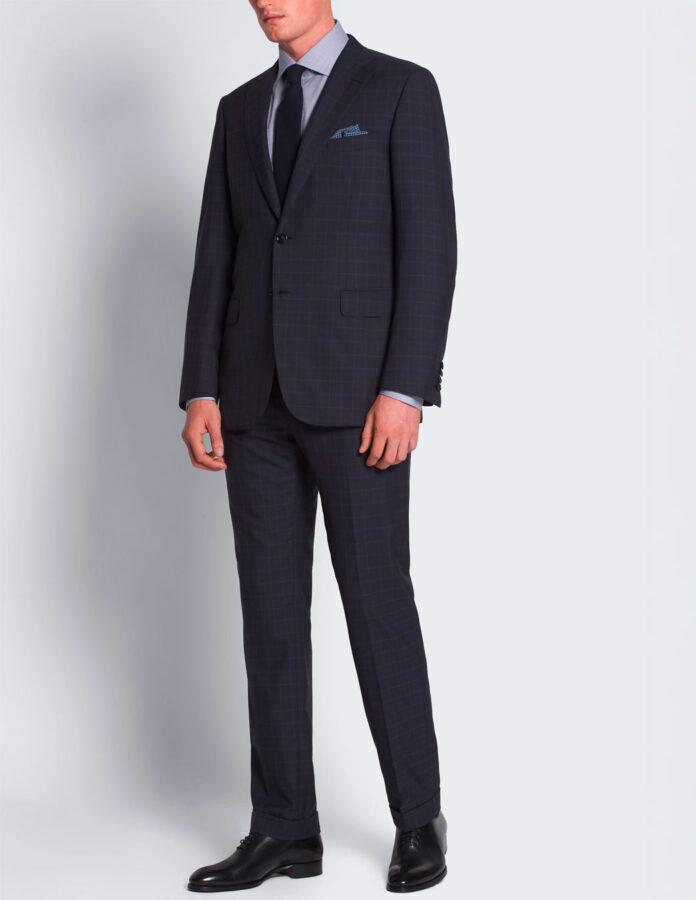 hombre visto de frente vistiendo un traje azul marino de cuadros ventana