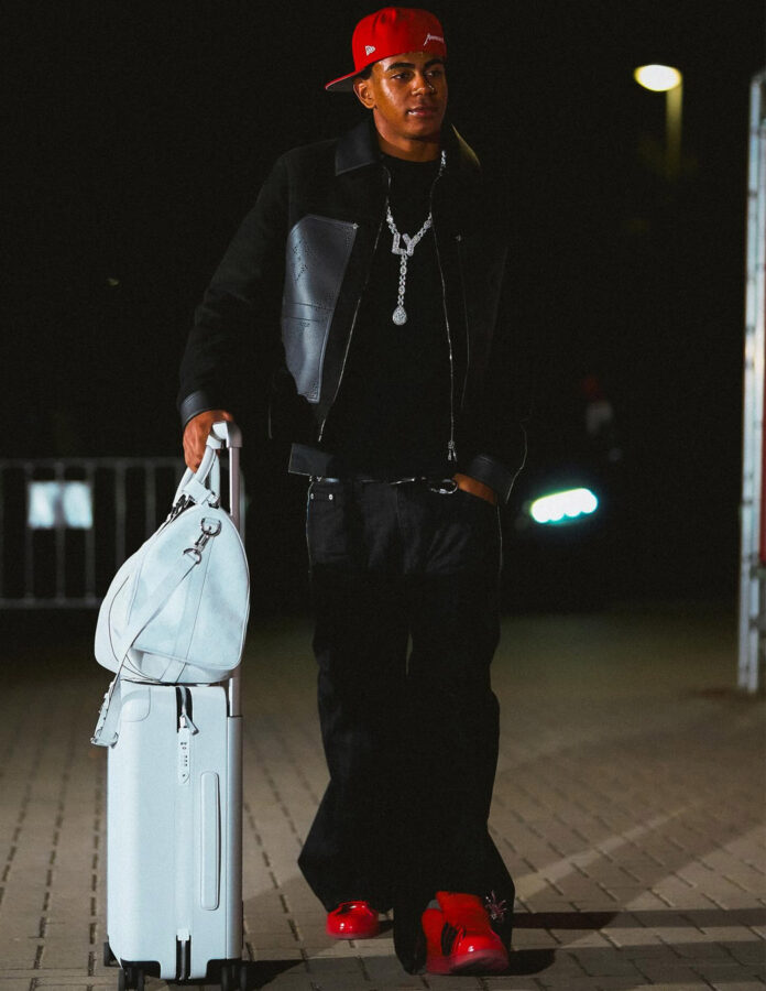 Lamine Yamal con chaqueta varsity negra, pantalones oversize y gorra roja.