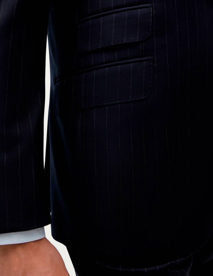 Foto detalle de un traje de rayas en el que se aprecia el bolsillo de la chaqueta, la manga y asomando el puño de una camisa.